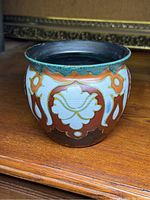 Front and side view of round Gouda vase showing decorative floral and geometric patterns with green flared rim.