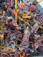 Mixed pile of university patches including letters, mascots and logos such as Trojan helmet and block monograms