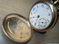 Pocket watch open showing white enamel dial with retailer signature and interior back cover stamping