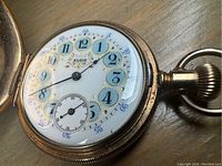 Close-up view of the watch face showing blue and gold accented numbers and black hands.