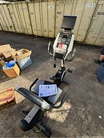 Full view of the Health Rider H30X recumbent bike showing seat, pedals, and large display monitor, captured outdoors on concrete surface.