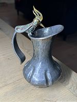 Oblique front view of hammered silver body and bird spout