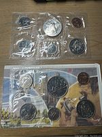 1979 and 1982 Canadian uncirculated coin sets sealed in plastic sleeves with original colored envelope for 1982 set visible underneath.