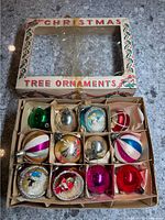 Photo showing open box of 12 vintage mercury glass Christmas bulbs with different colors and three diorama style ornaments.