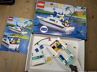Photo of opened box with disassembled fishing boat pieces, minifigures, and instruction manual inside the box
