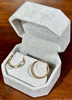 Pair of earrings displayed inside grey velvet jewelry box, front view.