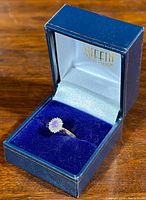 Ring displayed in Griffin Jewelry Designs box on wooden surface.