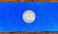 Front of silver 3 pence coin showing numeral '3' with a crown and wreath.