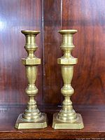 Front view of a pair of Victorian brass candlesticks, showing the polished solid brass and hexagonal design elements.