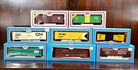 Nine Model Power HO scale freight cars in their original boxes arranged on a flat surface. Cars include various liveries and advertising for CN, CP Rail, and TH&B.