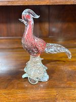 Full side view of the Murano glass rooster sculpture showing red aventurine breast, clear glass crest and tail, and clear base details.