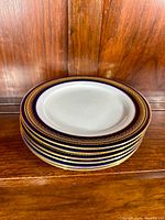 Stack of 6 Noritake Vienna dessert plates showing the white center and intricate cobalt blue and gold gilt border design.