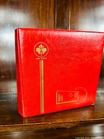 Photo of the closed red Uni-Safe brand binder with gold logo and text on the front and spine.
