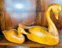 Photo showing two wood duck decoys, a duck and a swan, on a wooden shelf against wood paneling.