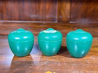 Front view of three green jars showing their shape and the partial foil label on the middle jar