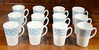 Twelve Royal Tuscan bone china mugs arranged in two rows on a wooden surface, showing uniform pattern and good condition.