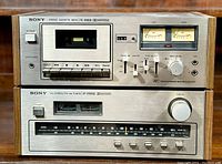 Photo of the Sony Stereo Cassette Tape Deck TC-1865D on top, and the FM Stereo/FM-AM Tuner ST-2950SD below, showing front interfaces, buttons, meters and wooden side panels.