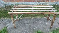 Full view of wooden antique collapsible laundry stand outdoors on concrete, showing structure and slats.