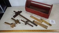 Wooden toolbox open with four wooden scribes and three folding rulers laid out