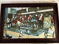 Framed lithograph print showing a lively hunting supper scene with men in red jackets, dogs, and a wood-paneled room interior.
