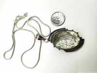 Photo showing the pendant and silver snake chain next to a Canadian dime for size reference.