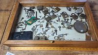 Wide overhead image of the wooden showcase displaying various locks and keys, showing the overall spread and condition.