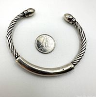 Front view of heaviy twisted rope pattern sterling silver open cuff bracelet displayed with a Canadian dime for scale.