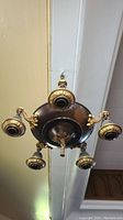 Bottom view showing the round central fixture with five ornate brass light holders extending outward.