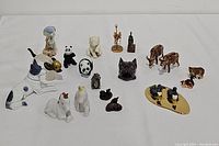 Wide view of all 19 assorted ceramic animal figurines showing various animals including dogs, pandas, cats, birds, cows, and people figurines.