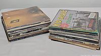 Two stacks of assorted used vinyl records placed side by side showing album covers and spines.