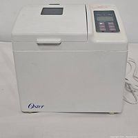 Front view of the closed white Sunbeam Oster Deluxe Model 4811 bread maker showing the viewing window on the top and the digital control panel on the right.