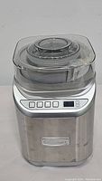 Front view of the stainless steel Cuisinart ice cream and yogurt maker with digital buttons and display, and clear plastic lid.