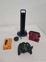 Lot includes a tall black CZUR Aura-B smart portable scanner, a red Grundig power generator with battery light and world band receiver, an orange electronic device with buttons and display, and a black wired Xbox controller.
