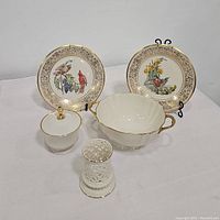 Photo showing all five Lenox china items grouped, including two decorative plates with bird designs on stands, a covered compote, a handled serving bowl, and a votive candle holder.