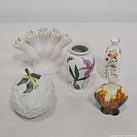 Group photo showing five different vases on a flat surface: tulipiere, botanical flower vases, hydrangea flower-shaped vase, and orange fish vase.