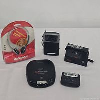 Five vintage portable sound devices and headphones shown together to illustrate contents of the lot.