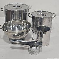 Photo showing all items in the set including two stock pots with lids, colander, masher, and measuring cup.