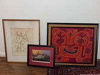 Three framed art pieces: clown artwork, needlepoint art, and Baltimore print