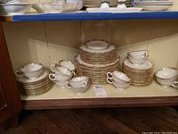 Wide shot of entire Lenox dish set with plates, saucers, and cups stacked inside cabinet shelf.