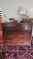 Front view of the closed secretary desk with four large drawers and round wooden knobs, showing scratches.