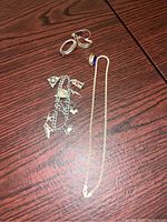 Full lot including chain with blue stone pendant, charm bracelet with multiple silver charms, two earrings (one twisted oval, one leaf-shaped), and a pin