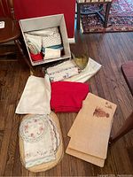 Box of assorted napkins and folded tablecloths arranged on the floor
