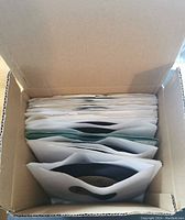 Top-down view of a cardboard box filled with vertically stored paper sleeves containing vinyl 45 RPM records, showing neat orderly storage.
