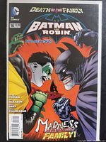Cover of Batman and Robin comic book issue #16 from The New 52 by DC Comics featuring the Joker and Batman with dramatic expressions and ‘Madness Rides the Family’ text.