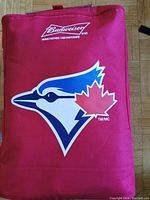 Front view of bright red Toronto Blue Jays cooler bag with large bird logo featuring a red maple leaf, Budweiser logo above.