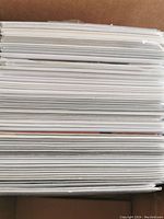 Stack of comic books in protective sleeves viewed from top, showing tight packed white pages.