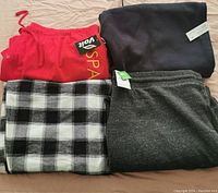 Four pairs of men's 2XL bottoms: three track pants and one pajama pants. Red, black, gray speckled, and black-and-white plaid colors visible.