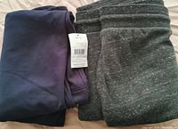 Folded navy blue and grey jogger pants showing tags and speckled detail on grey pair