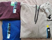 Three men's 3XL tops featured: burgundy golf style shirt, blue sleeveless shirt, and beige full zip-up hoodie all new with tags.