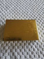 Sealed gold-plated playing card deck box showing embossed Canadian $1000 bill design with portrait and text.